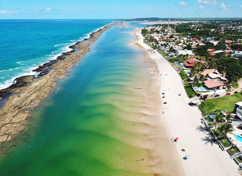 A coastal town with a long sandy beach, clear blue ocean, and residential buildings. 5