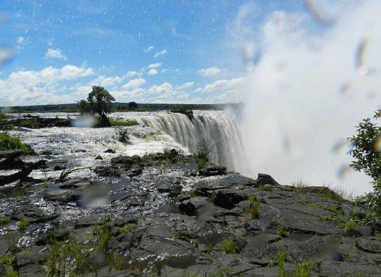 A waterfall cascading over rocks with a clear sky above. 3