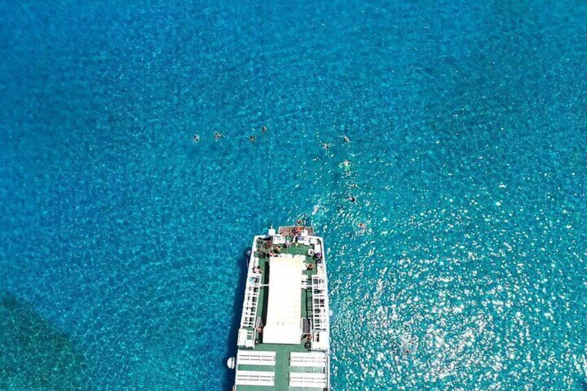 An aerial view of a ship with people swimming in the water around it. 5