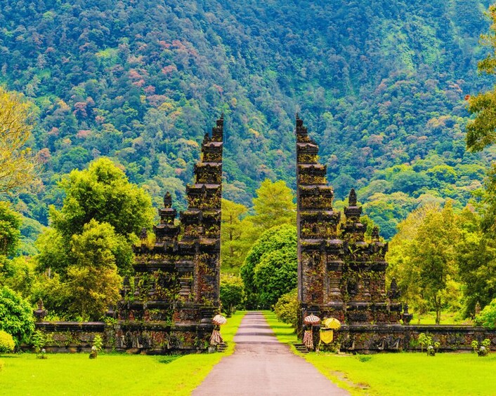A temple with two towers, surrounded by lush greenery and a forested hillside. 2