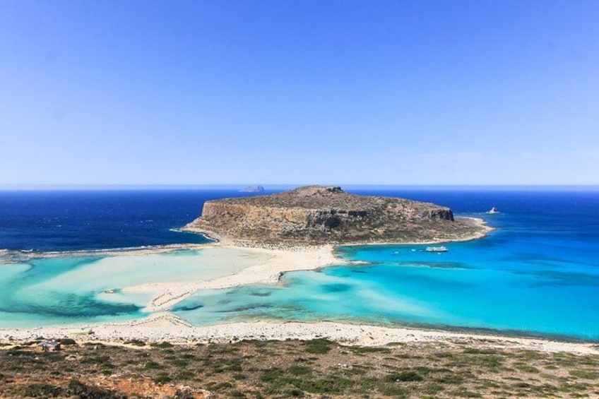 Eine Küstenlandschaft mit einer markanten Felsinsel, umgeben von türkisfarbenem Wasser und einem Sandstrand. 3
