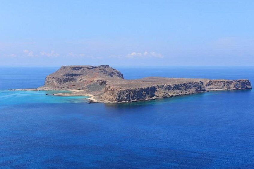 A coastal landscape with a prominent rocky outcrop and clear blue waters. 5