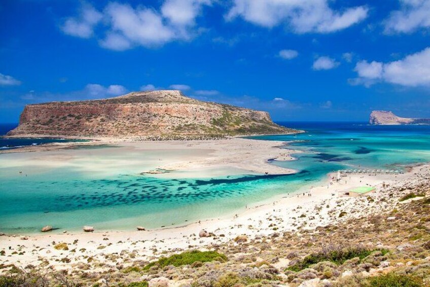 Eine Küstenlandschaft mit Sandstrand, klarem türkisblauem Wasser und felsigen Klippen. 4
