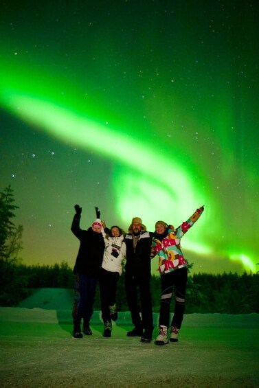 Four people posing under the Northern Lights. 3