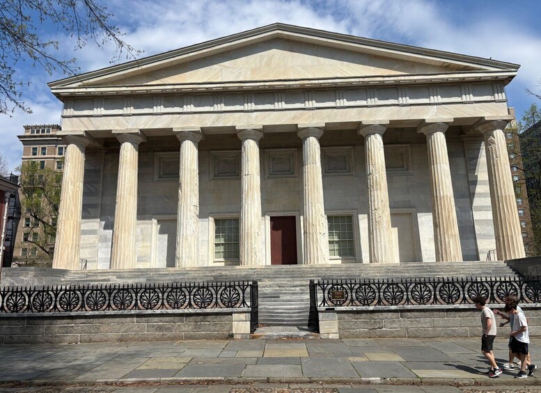 A neoclassical building with a portico of columns, a central entrance, and a decorative iron fence. 3