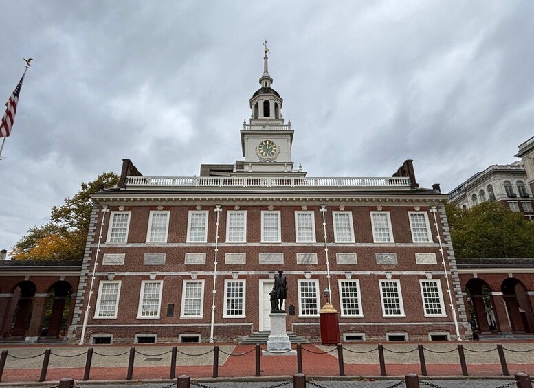 A historic building with a clock tower, a statue, and an American flag. 5