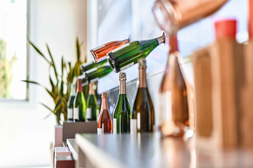 A row of wine bottles on a counter with a window in the background. 2