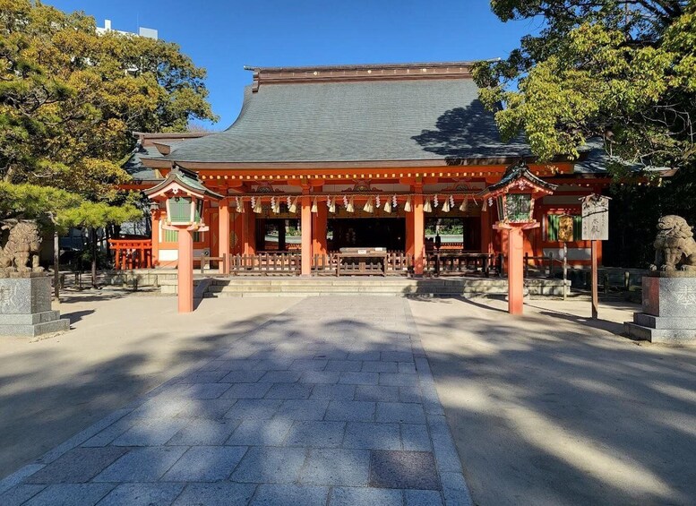 A traditional Japanese temple with a curved roof, red pillars, and a stone pathway leading to the entrance. 4