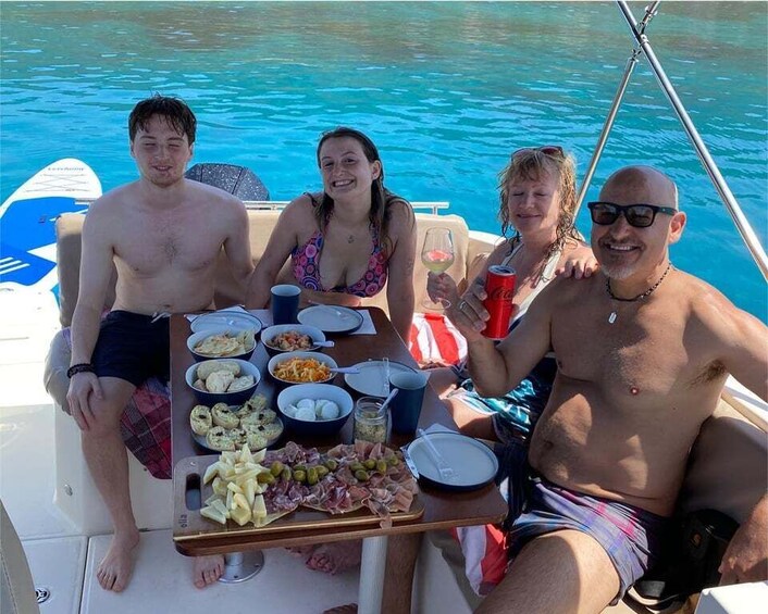 Four people on a boat with a table of food and drinks. 4