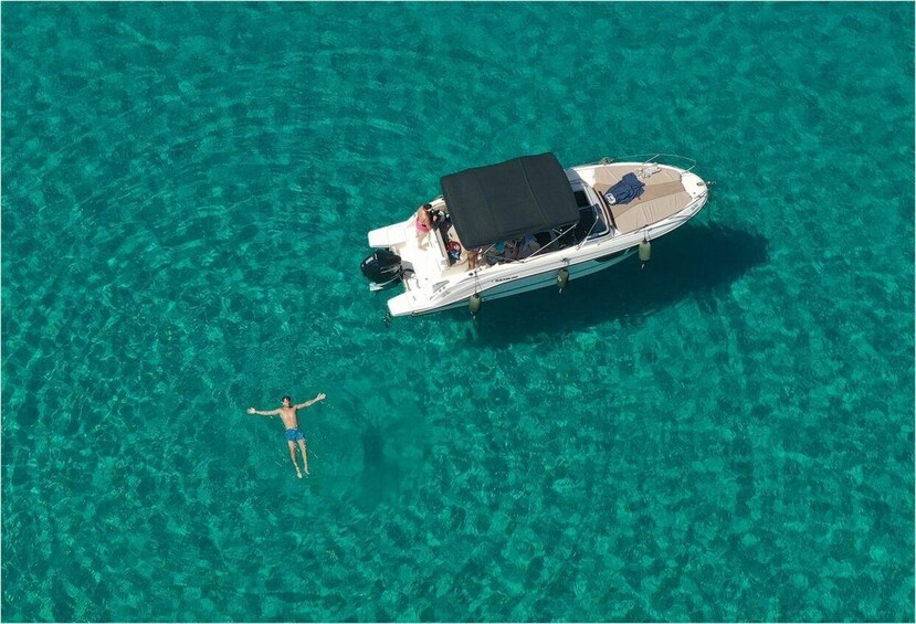 A boat with a covered deck and people on it, floating on clear turquoise water. 3