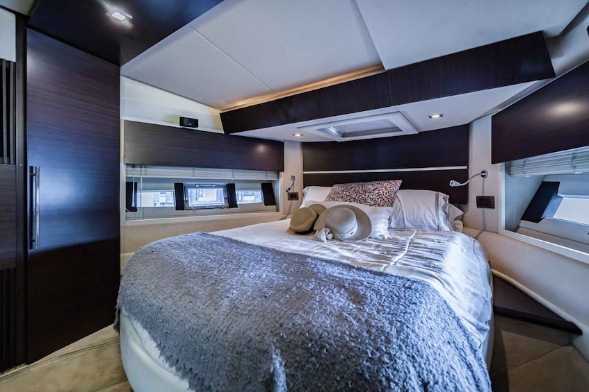 A modern bedroom with a large bed, dark wood paneling, and a window with blinds. 4