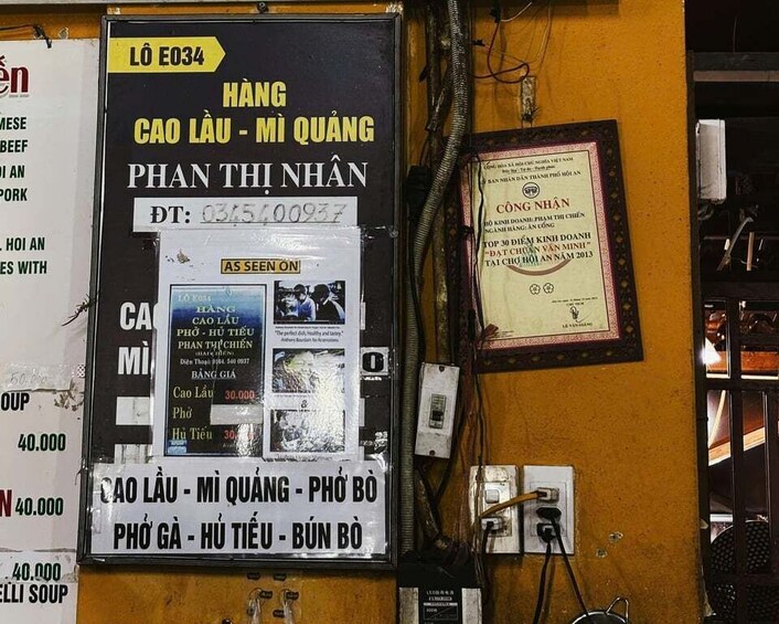 A wall with various signs and posters, including a menu board and a framed certificate. 2