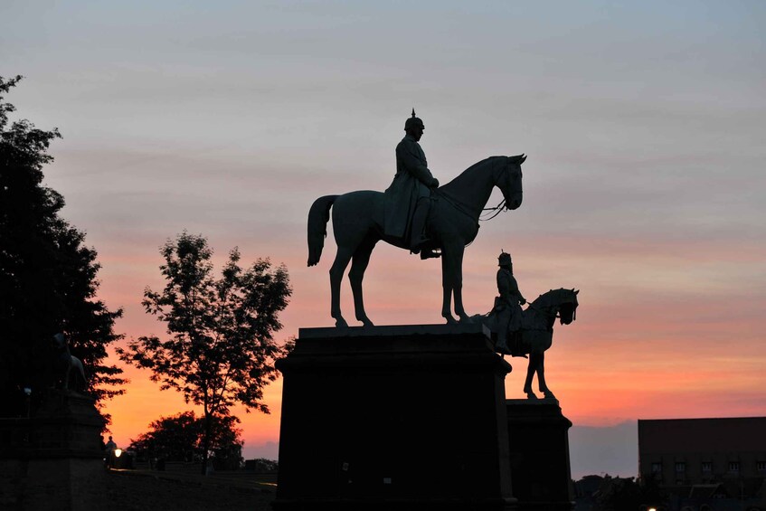 A statue of a person on horseback, set against a sunset sky. 3