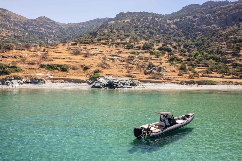 A clear lake with a motorboat, surrounded by dry hills and sparse vegetation. 5