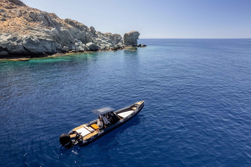 A small boat on clear blue water near rocky cliffs. 2