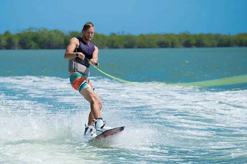 A person wakeboarding on a body of water with trees in the background. 2