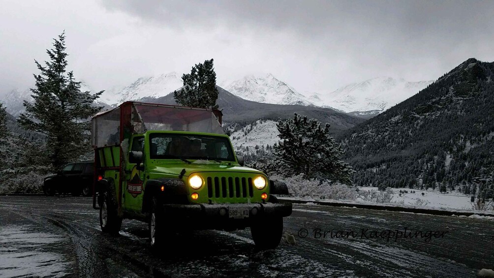 Un vehículo todoterreno verde con una cabina para acampar en una carretera nevada de montaña. 5