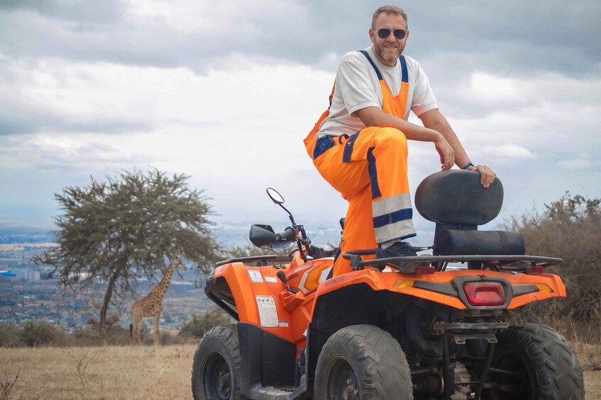 Una persona conduce un vehículo todo terreno naranja con un paisaje urbano y una jirafa al fondo. 1