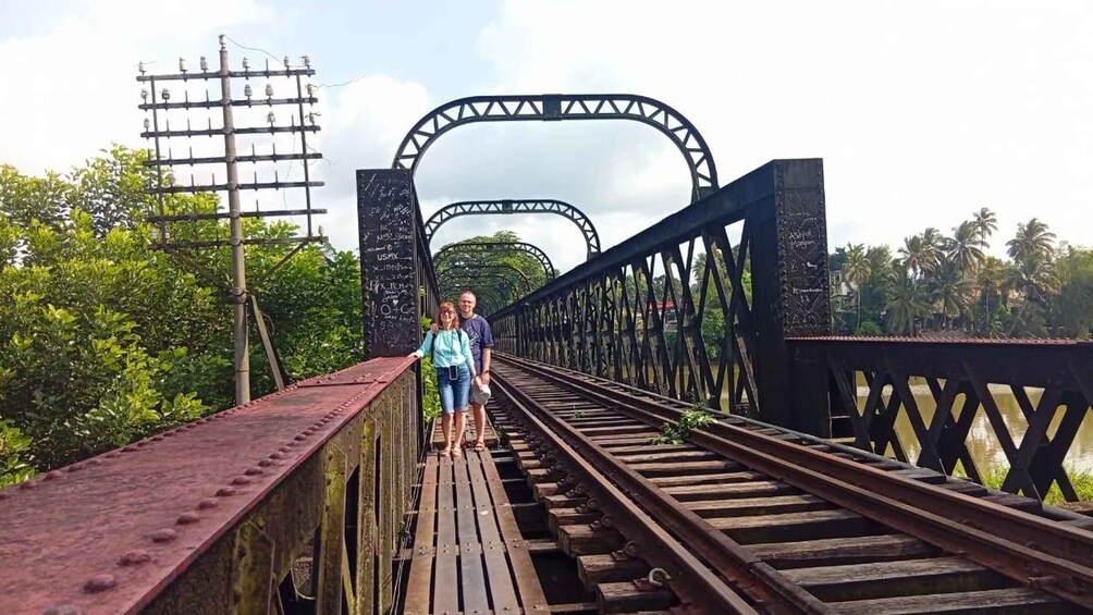 A bridge with a metal arch and wooden planks, surrounded by greenery. 4