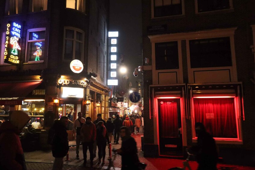 Vilkas katu yöllä, jossa on valaistuja kylttejä, kuten esimerkiksi kyltit, joissa lukee «Old Sailor Bar» ja «Cafe». 5
