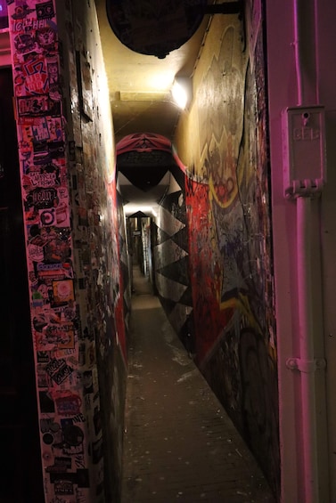 Kapea kujanne, jonka seinät on peitetty graffiteilla ja jonka katto on kirkkaasti valaistu. 2