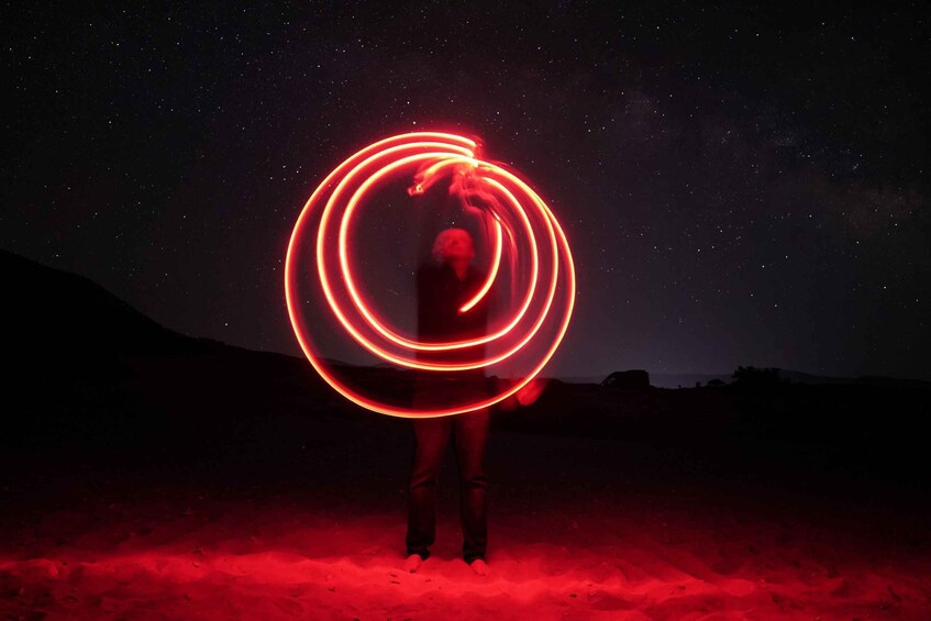 A person with a glowing red light ring, standing in a desert at night. 5