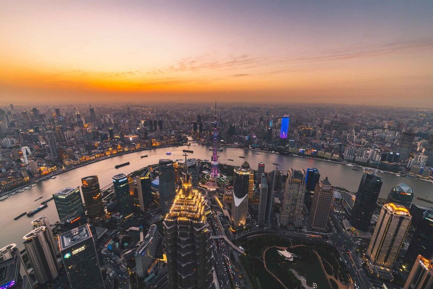 A cityscape at sunset with a river, illuminated buildings, and a prominent tower. 3