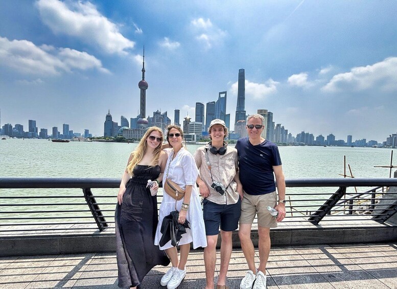 A group of people posing on a waterfront promenade with a city skyline in the background. 1