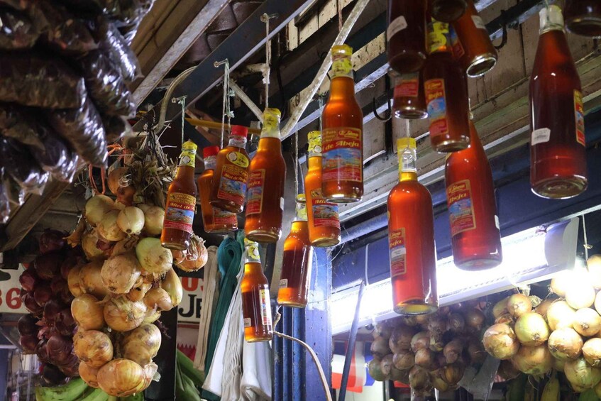 A market with hanging bottles of sauces and onions. 2