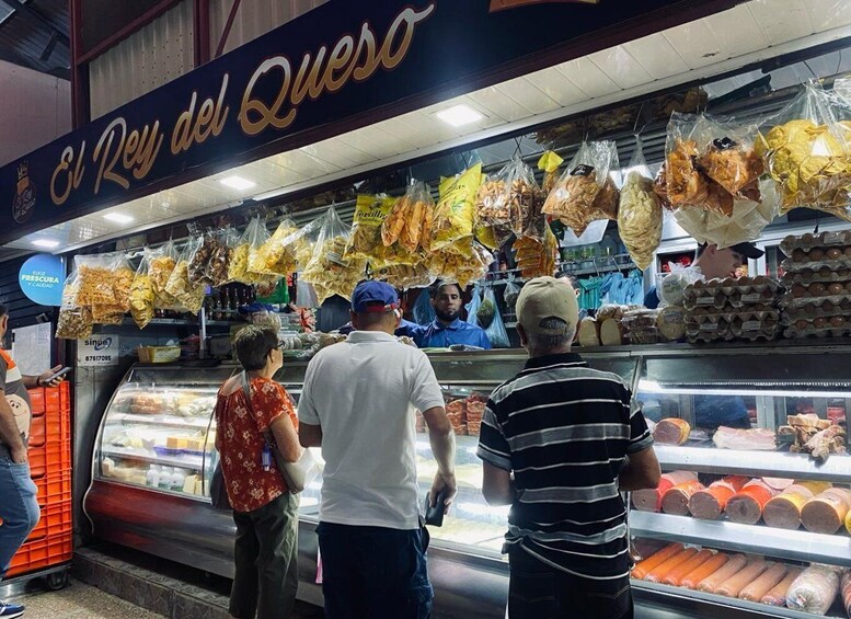 A market stall with various food items, including hanging bags of snacks and a display case with packaged goods. 1