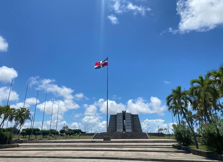 A clear sky with a flag, palm trees, and a pyramid-like structure. 3