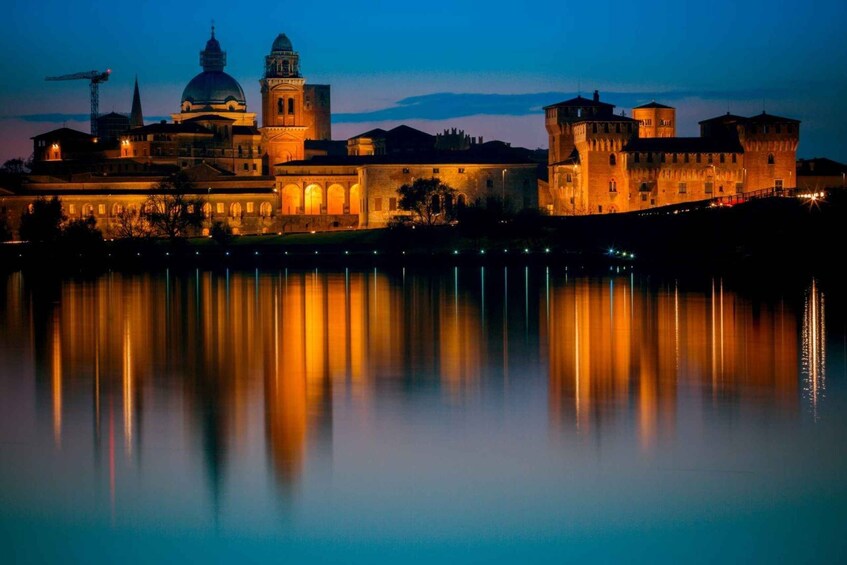 A historic building complex with a large dome and towers, reflecting on a calm body of water at dusk. 5