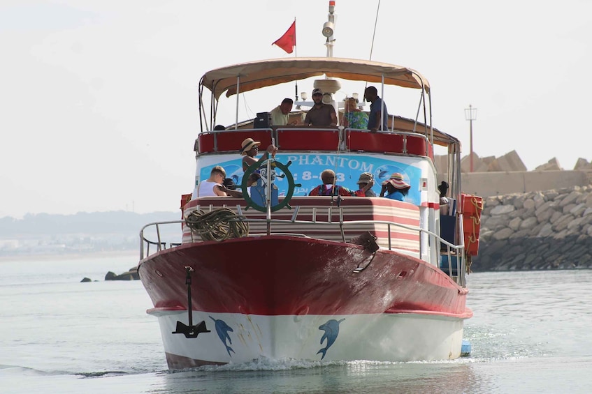 A red and white boat named 'Phantom' with dolphins on its side, moving through calm water. 2
