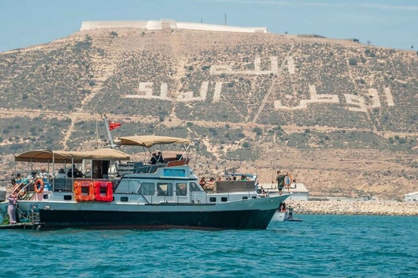 A boat on calm waters with a rocky hill in the background. 5