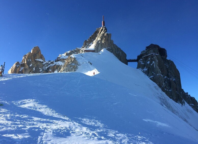A snow-covered mountain peak with a ski lift and a person skiing down the slope. 2