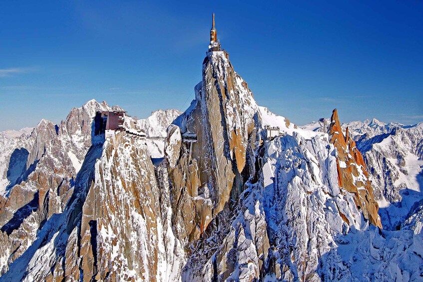 A snow-covered mountain peak with a small structure at its summit. 3