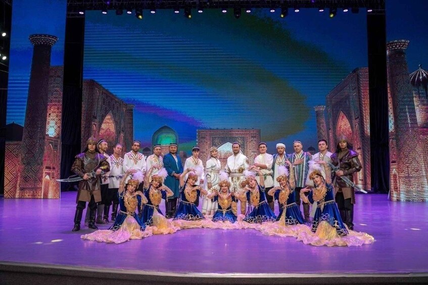 A group of people on a stage with a backdrop of a cityscape and a large screen displaying a similar cityscape. 2