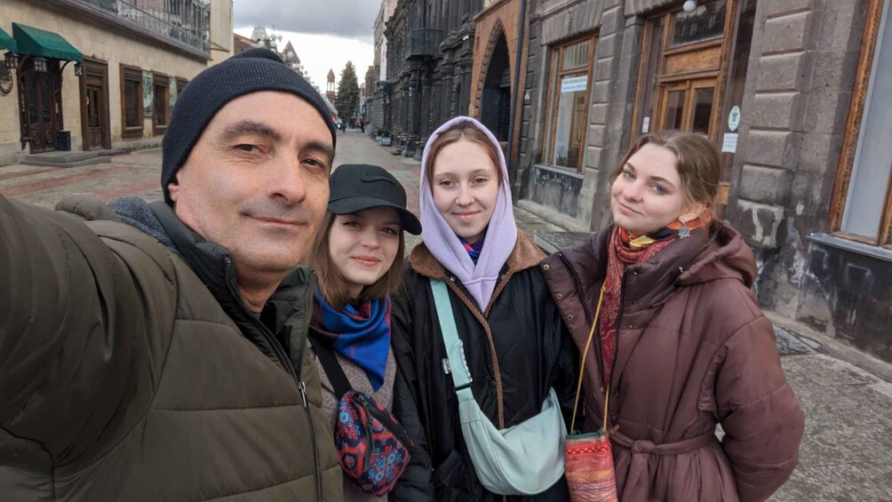 A group of people taking a selfie on a street with historic buildings. 1