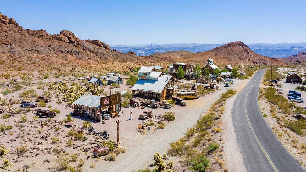 A desert town with buildings, vehicles, and a road. 2