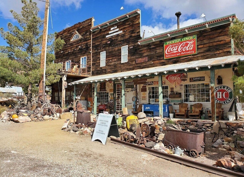 A rustic building with a Coca-Cola sign, vintage furniture, and mining equipment. 5