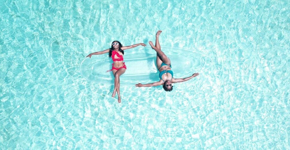 Two people floating in a clear blue pool. 3