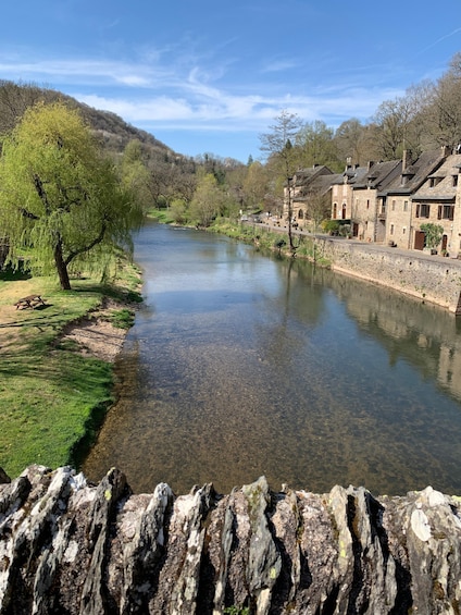 A river flowing through a town with stone buildings and a willow tree. 2