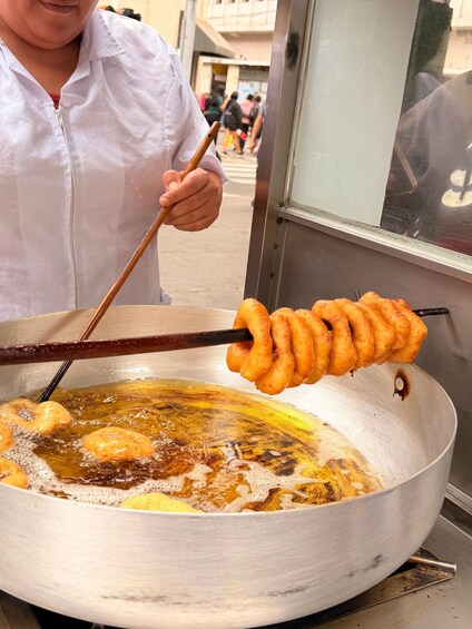 A person frying doughnuts in a large pan. 5