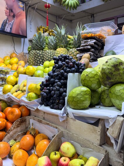 A variety of fruits including oranges, apples, grapes, and pineapples displayed in a market setting. 2