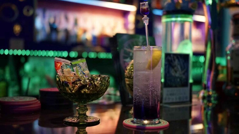 A bar setting with a cocktail in a tall glass and a bowl with snacks. 5