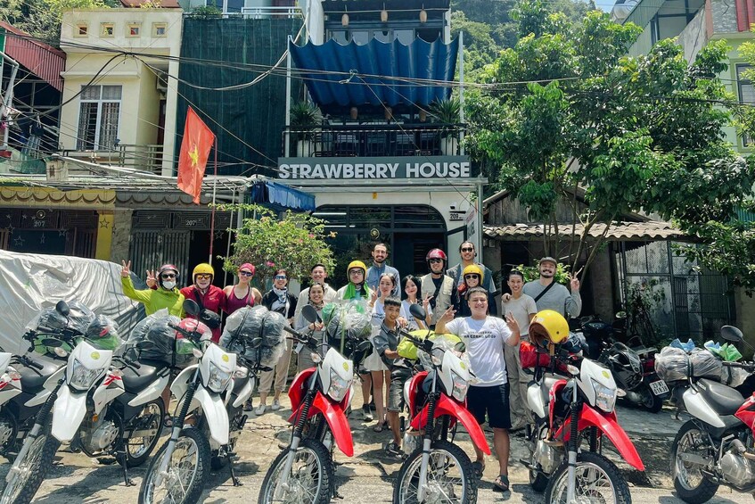 A group of people posing with motorcycles in front of a building labeled "Strawberry House." 3