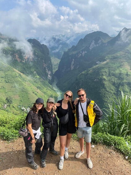 A group of people standing on a dirt path with a mountainous landscape in the background. 2