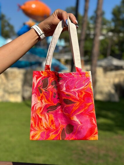 A hand holding a colorful tote bag with a vibrant floral pattern. 3