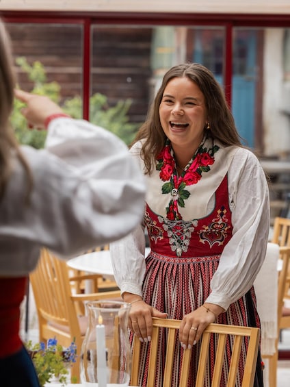 A person in traditional attire with a floral necklace, seated at an outdoor table with a candle. 2