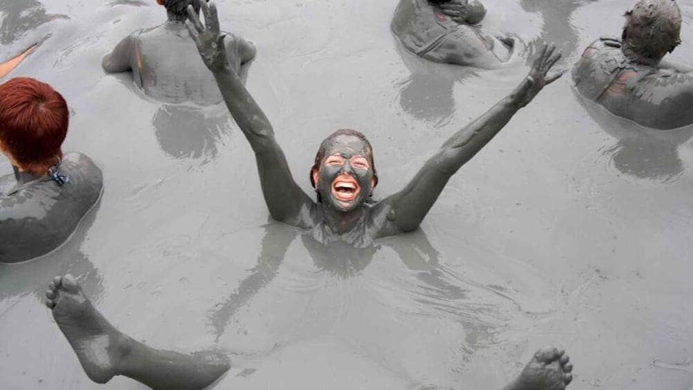 A person covered in mud, surrounded by others in a muddy environment. 5